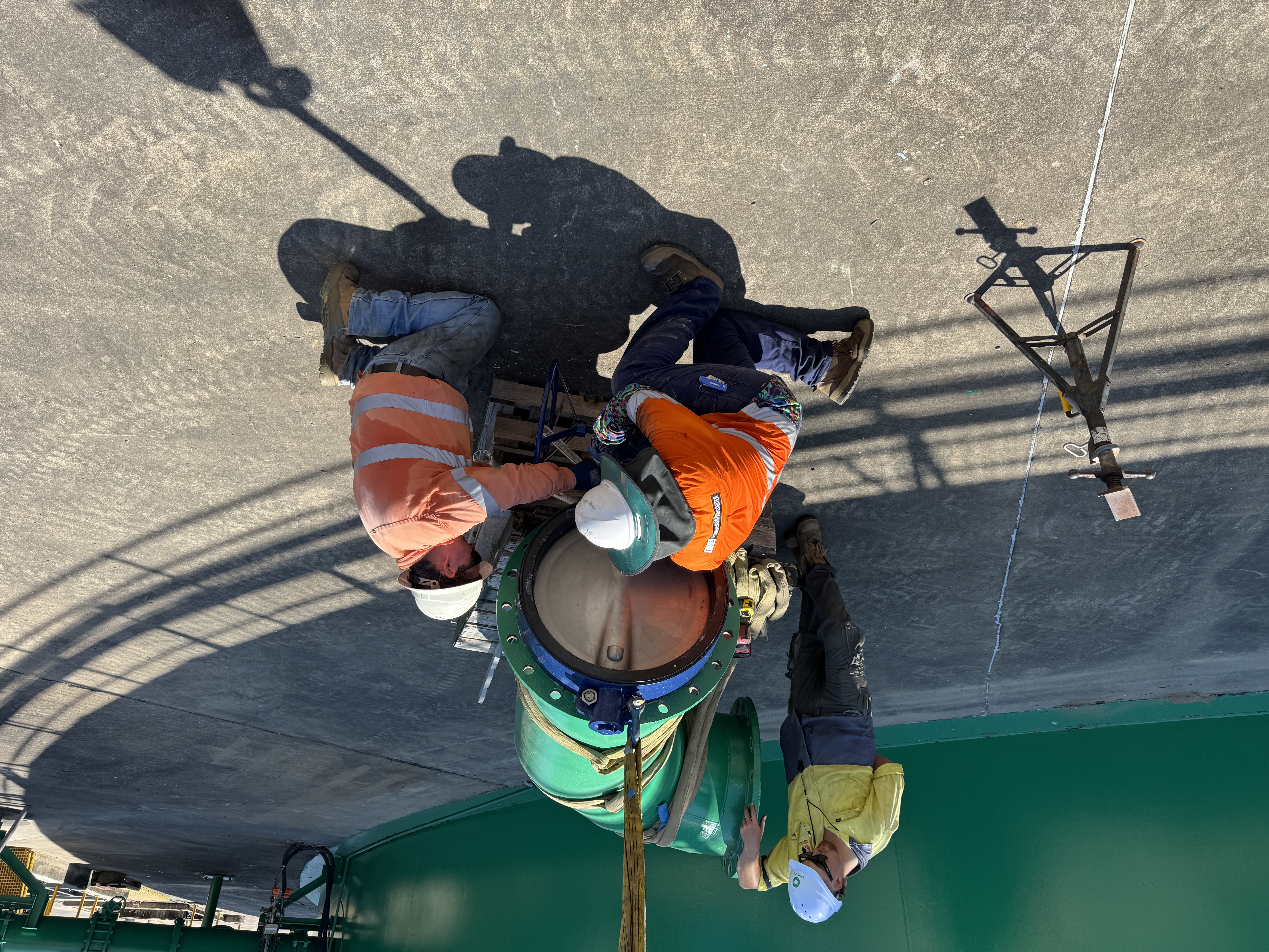 Vision crew installing tank access port — overhead mechanical works